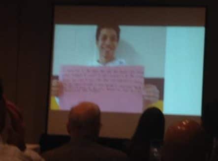 image of student holding up handwritten sign on screen during presentation