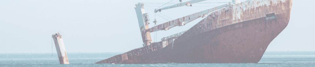 Large red industrial fishing ship sinking from the back of the boat with the front end sticking up in the air.